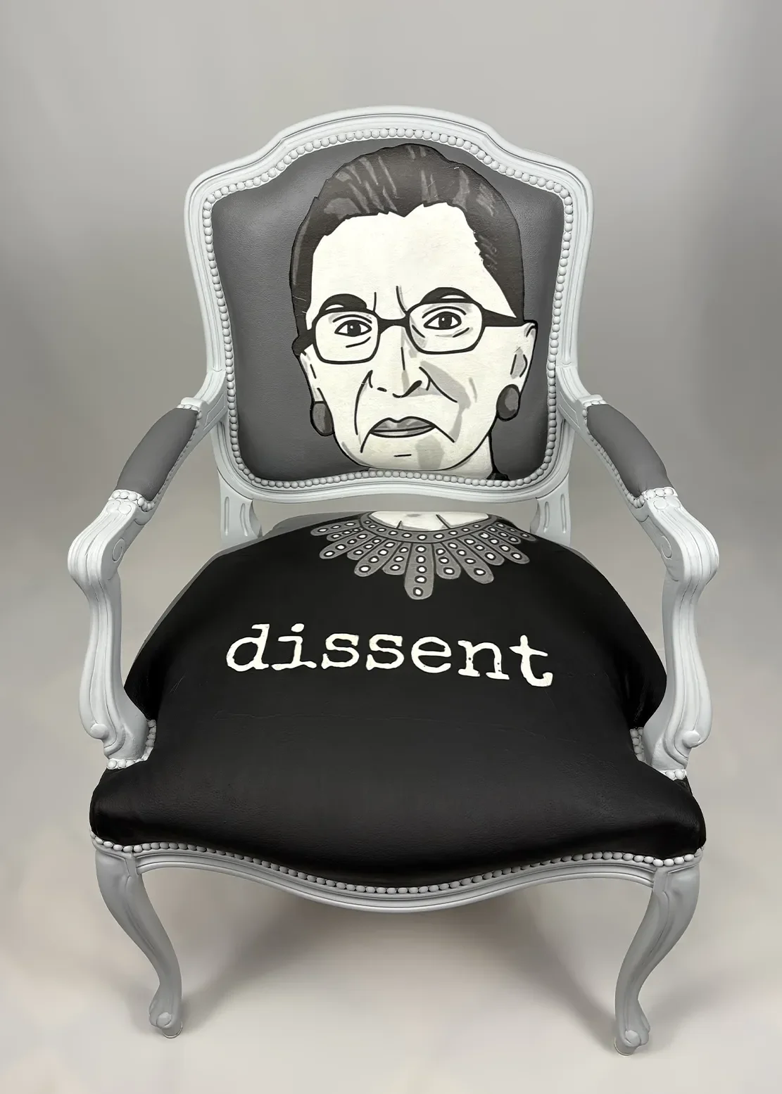 Artistic chair with a portrait of Ruth Bader Ginsburg on the backrest and the word 'dissent' written on the seat.