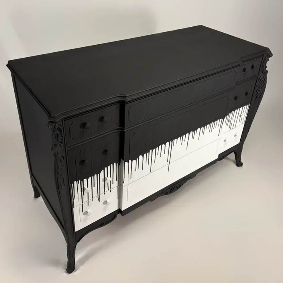 A black dresser designed to look like piano keys, with black top and sides, and white drawer fronts decorated with black drips.