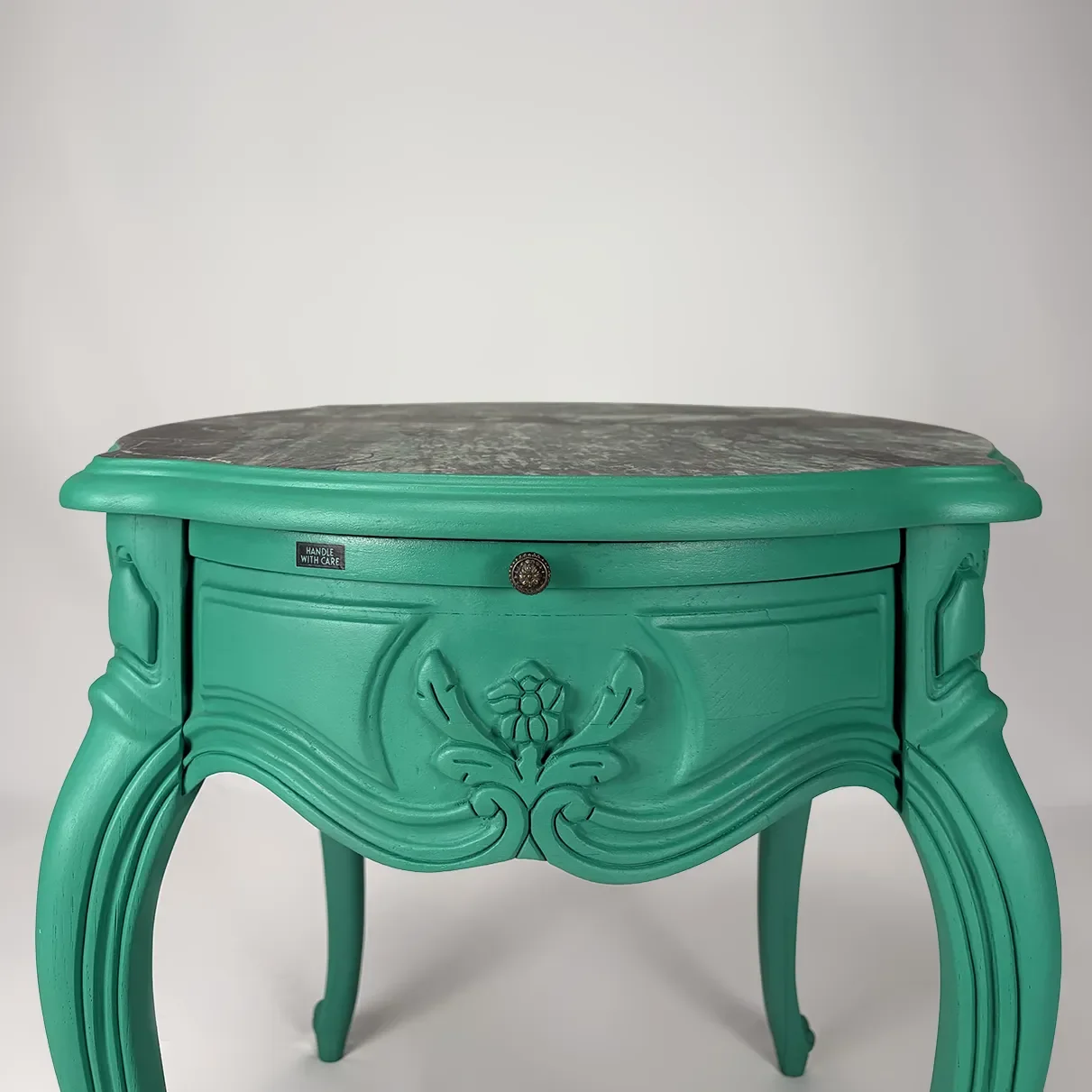 Vintage green ornate side table with a dark top and decorative carvings.
