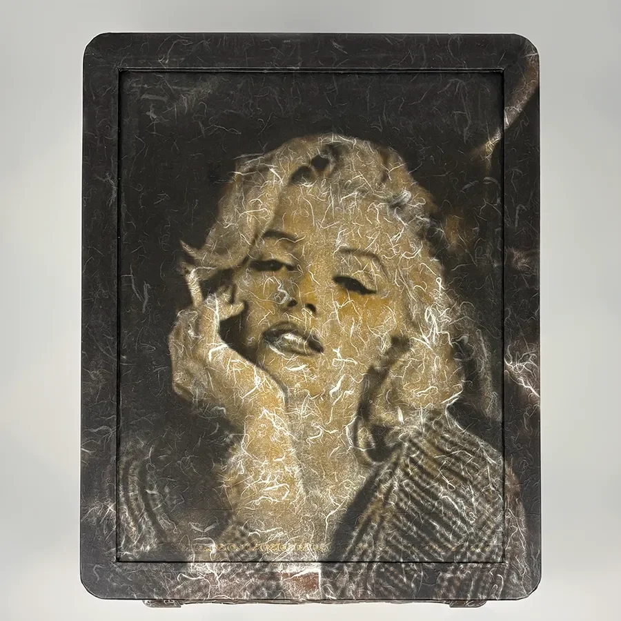 A mixed media artist's depiction of Marilyn Monroe with a dark background, featuring a textured, cracked artistic style.