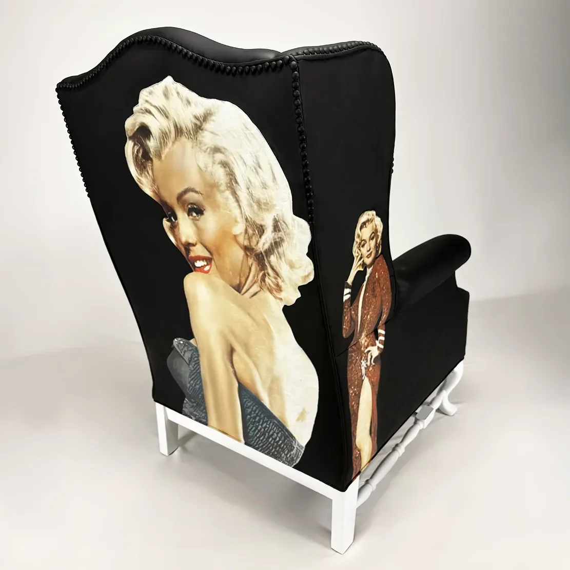 A black upholstered armchair with vintage images of Marilyn Monroe on the sides and back, set against a neutral background.