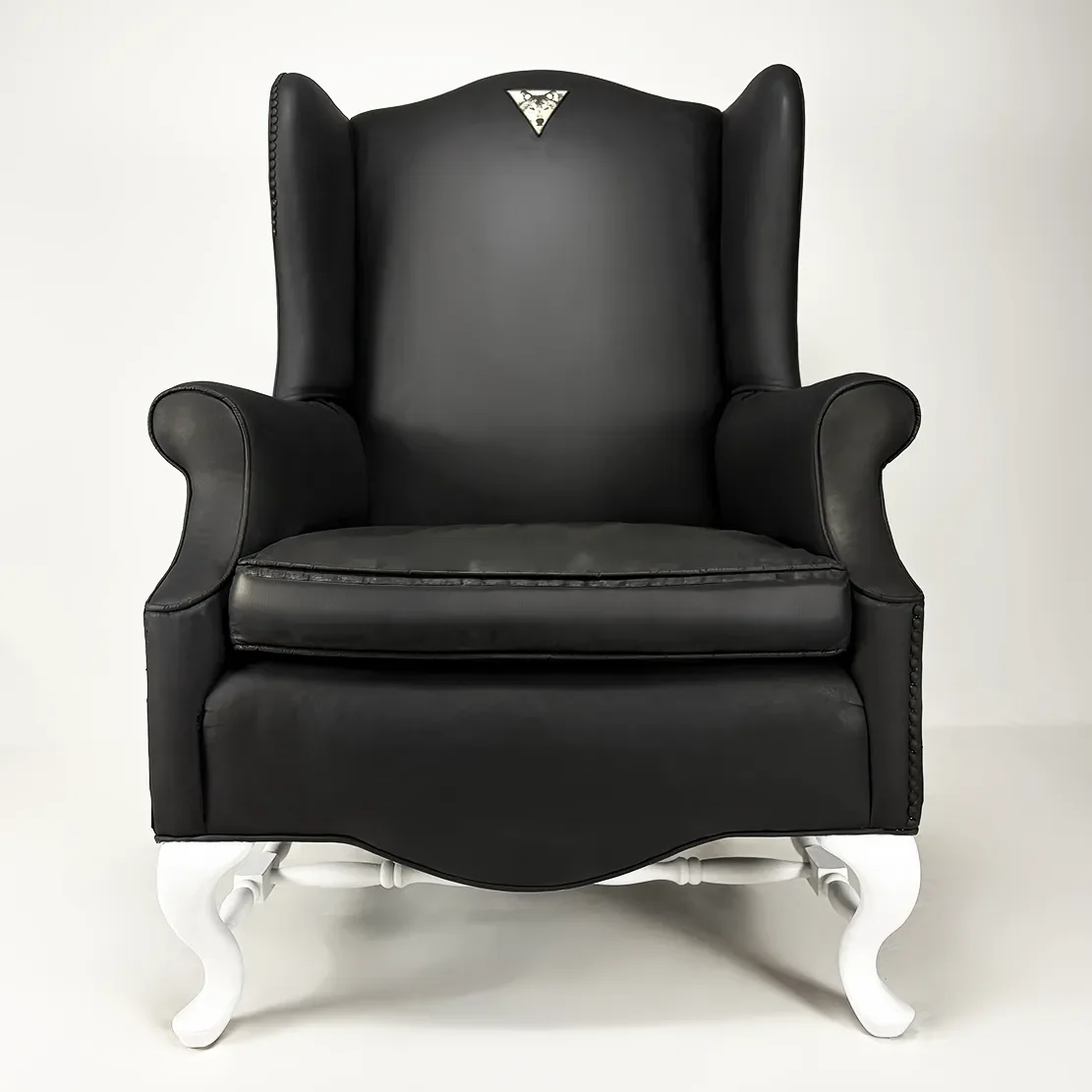 Black leather high-back armchair with white ornate legs against a plain background.
