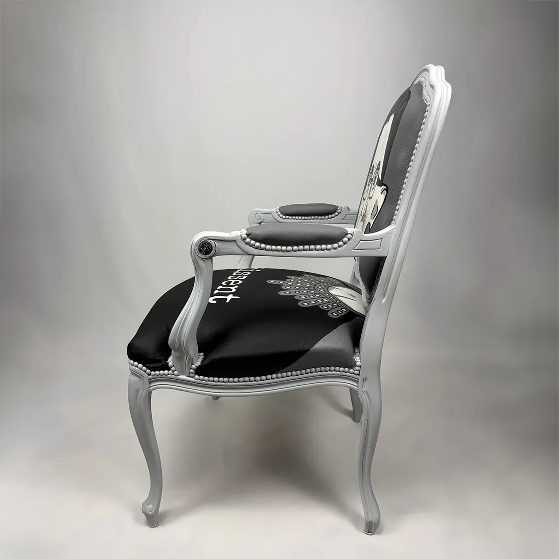 A vintage-style armchair with a grey wooden frame, black and white upholstery, and decorative details.