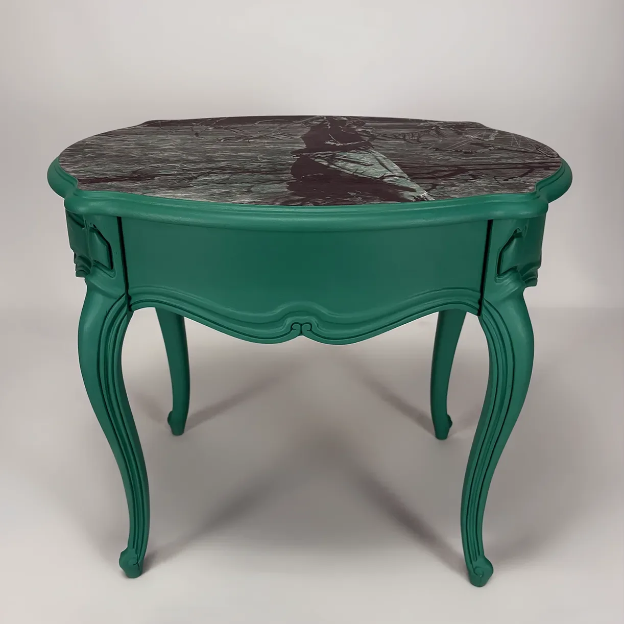 A vintage-style table with ornate teal legs and trim, topped with a dark marble surface.