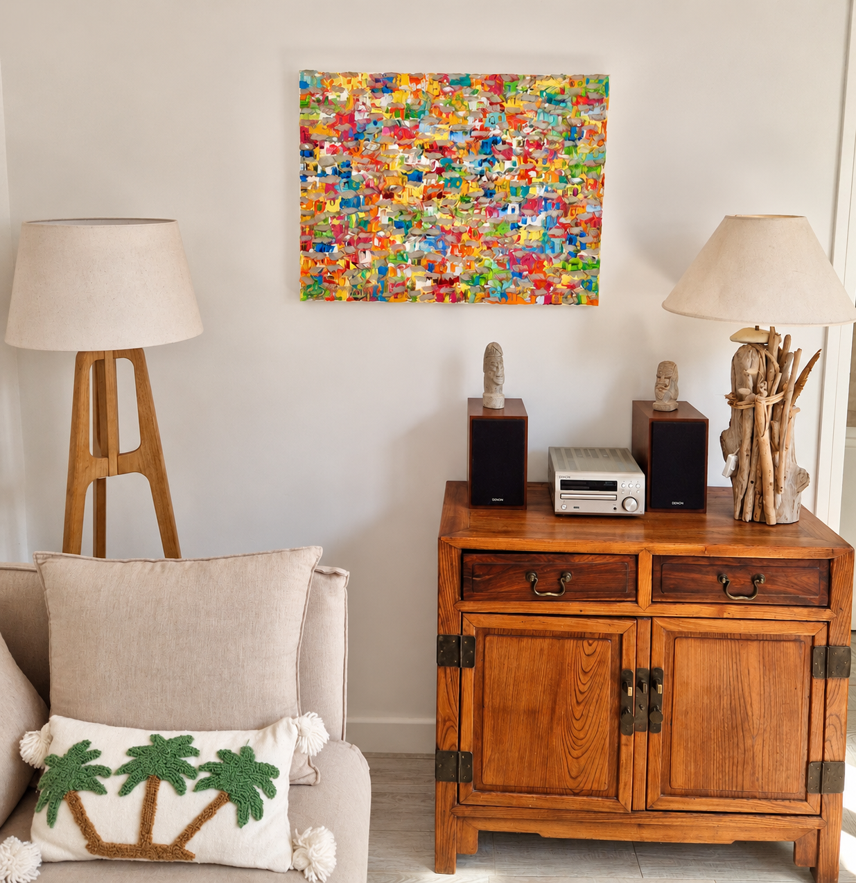 Colorful favela painting Felicidade Carioca by Christine Drummond displayed in a beach house in Médoc, France, above a wooden cabinet in a bright coastal interior.