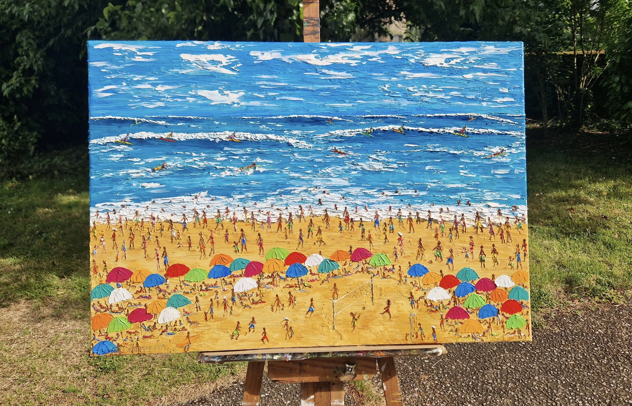Energia Carioca by Christine Drummond displayed on an easel outdoors, vibrant Rio beach painting with surfers, colourful umbrellas and expressive palette knife textures.