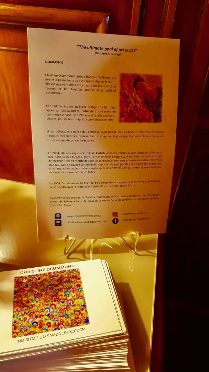 Artist biography and exhibition materials for Christine Drummond displayed at the Echoes da Brasilidade event at Hotel Regina Louvre in Paris in 2025.