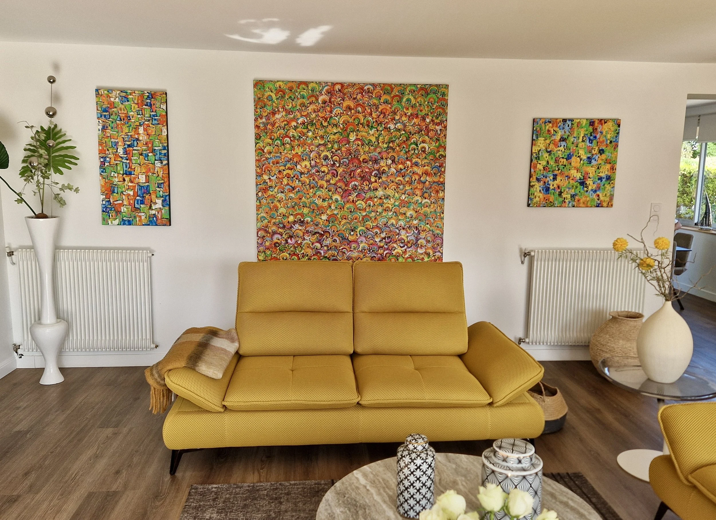 Christine Drummond colourful contemporary painting displayed above mustard yellow sofa in modern French interior