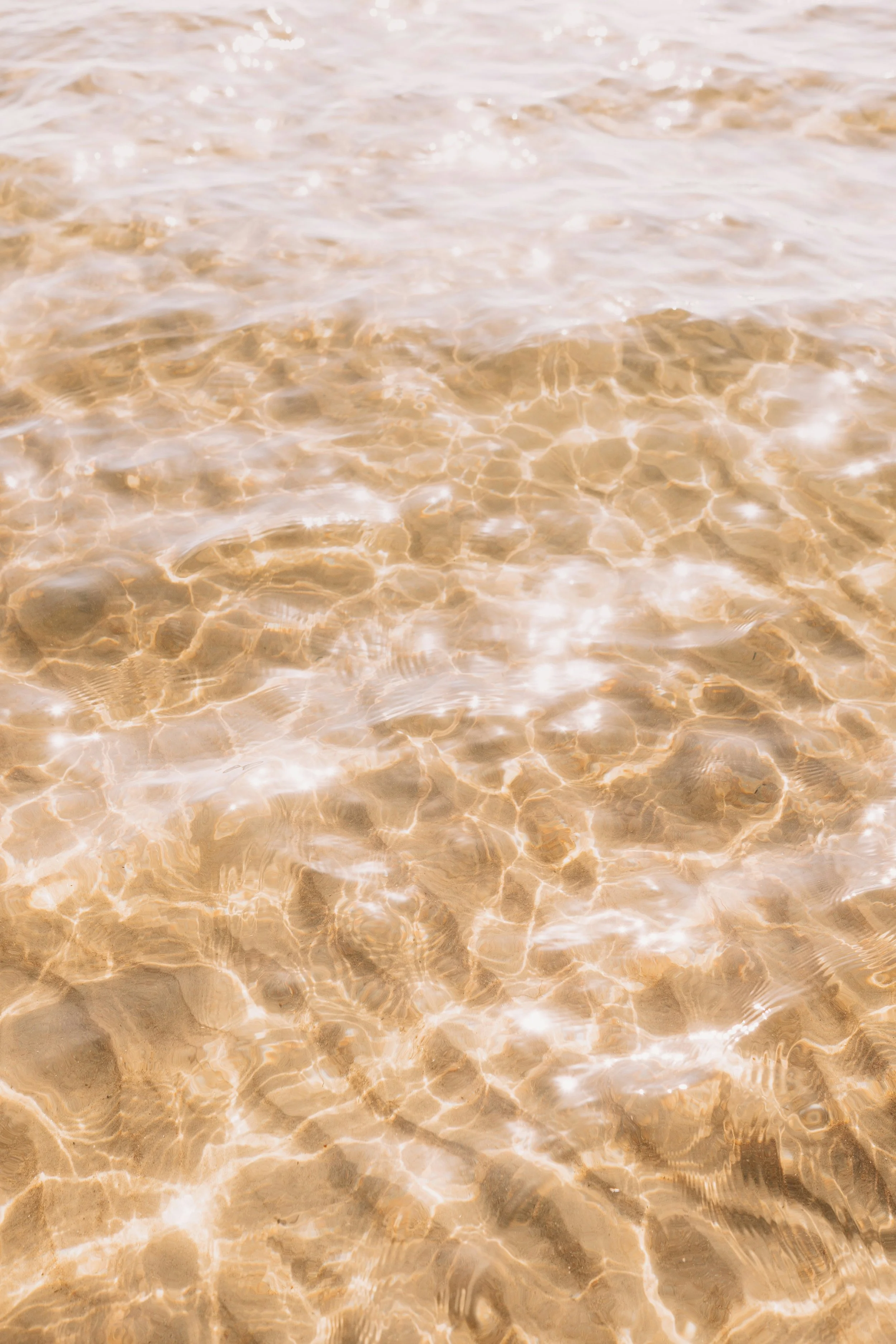 Clear shallow water at the beach with sunlight reflections.