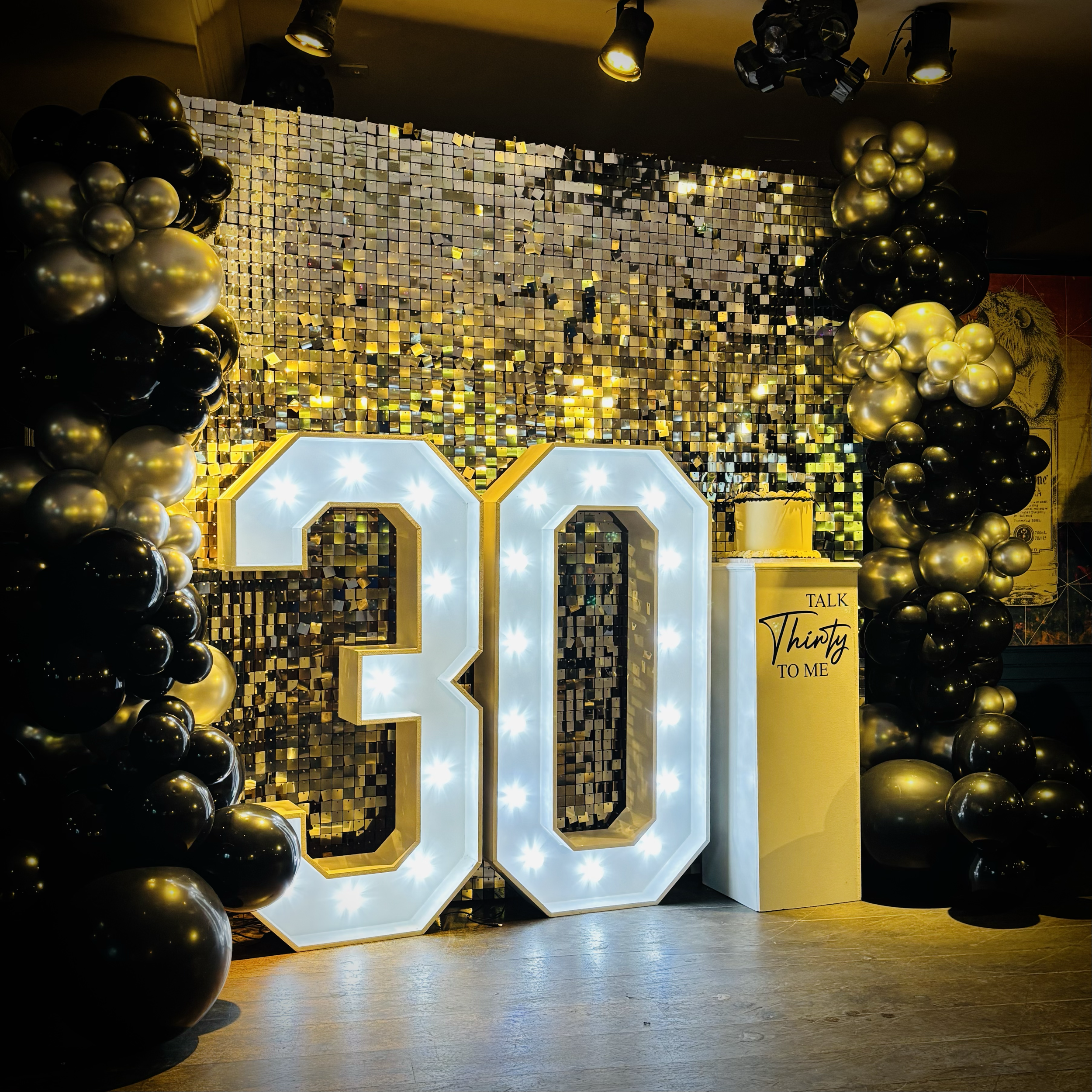 Gold shimmer wall, balloon decoration, light uo '30' and personalised cake stand at Revolution Bar in Cambridge
