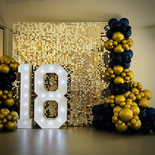 Champagne Gold Shimmer Wall with balloon decor and light up number 18 for a birthday party at Cottenham Village Hall 