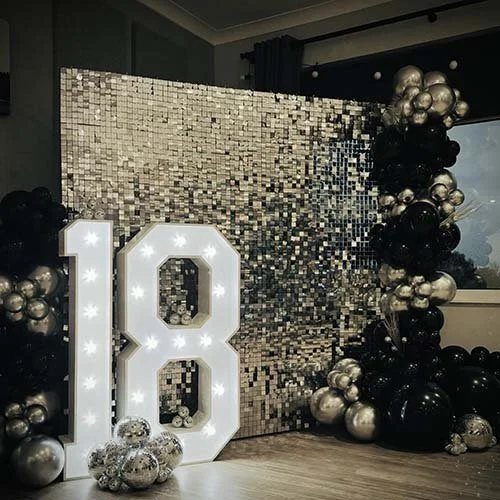 Silver shimmer wall with silver and black balloon decor, disco balls and light up 18 for a party at Ely Golf Club