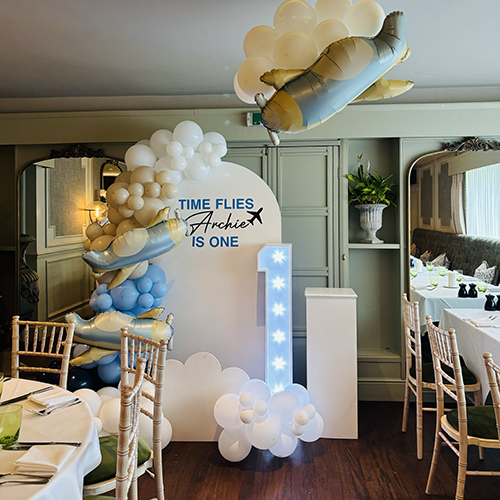 Personalised background with balloon decor and light up number 1 and balloon cloud clusters with airplanes