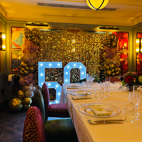 Gold shimmer wall with gold, pink and cream ballon decor and light up 50 at The Ivy in Cambridge 