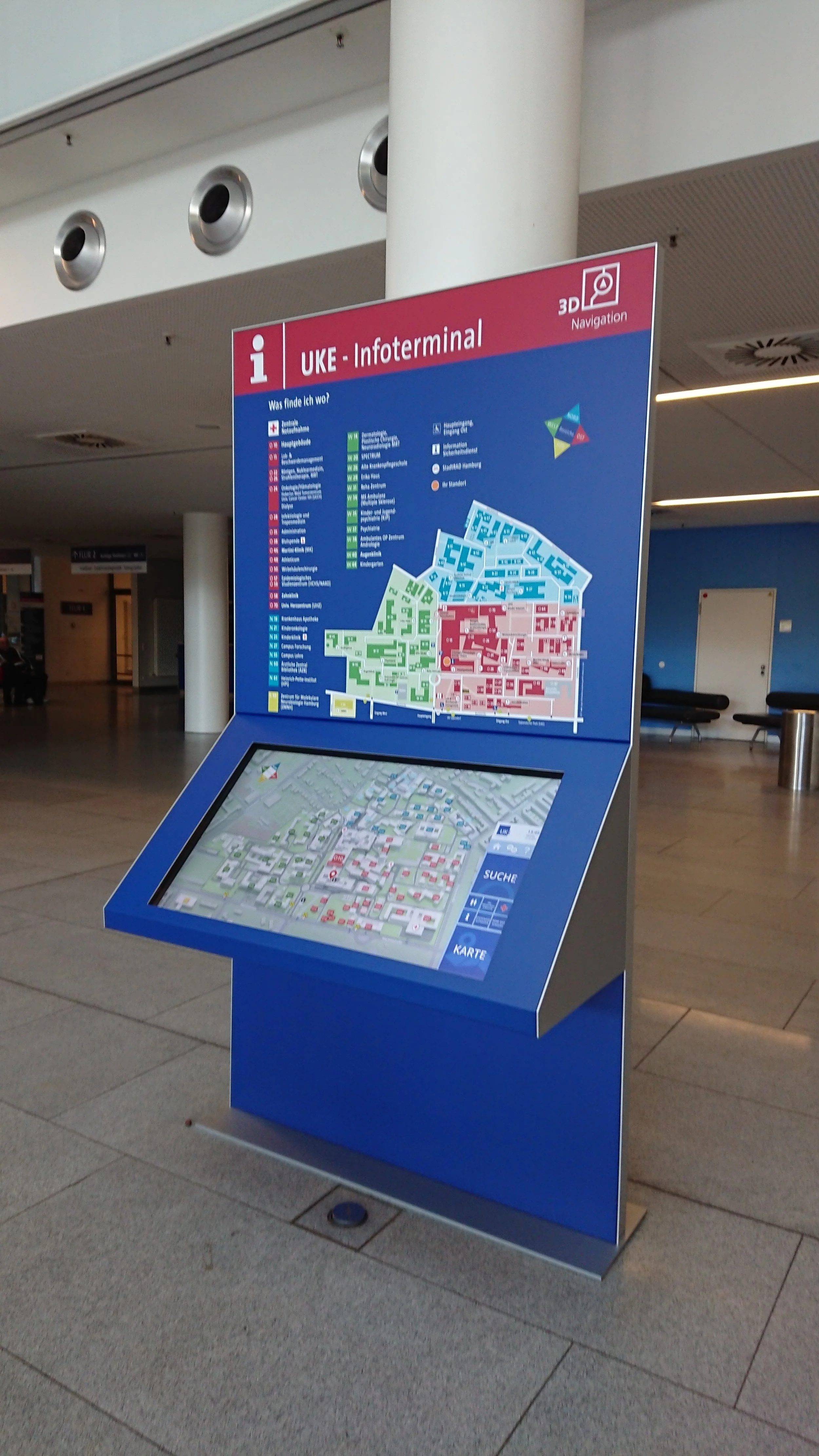 Ein Informationsstand mit einem digitalen Touchscreen und einem Stadtplan, beschriftet mit 'UKE - Infoterminal' in einem öffentlichen Gebäude.
