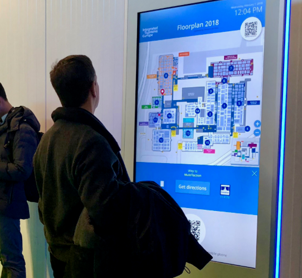 Ein Mann schaut auf einen digitalen Lageplan eines Gebäudes in einer öffentlichen Einrichtung.