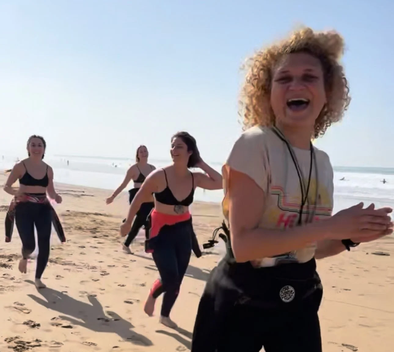 Group of women running on a sandy beach on a sunny day.