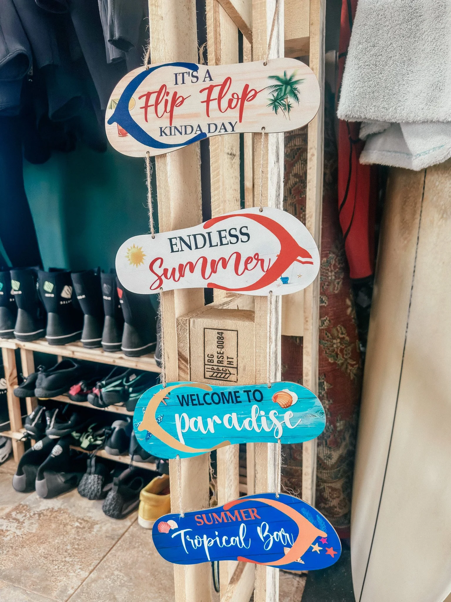 Stacked colorful signs with summer themes, including messages like "It's a Flip Flop Kinda Day," "Endless Summer," "Welcome to Paradise," and "Summer Tropical Bar," decorated with images of flip flops, palm trees, and seashells.
