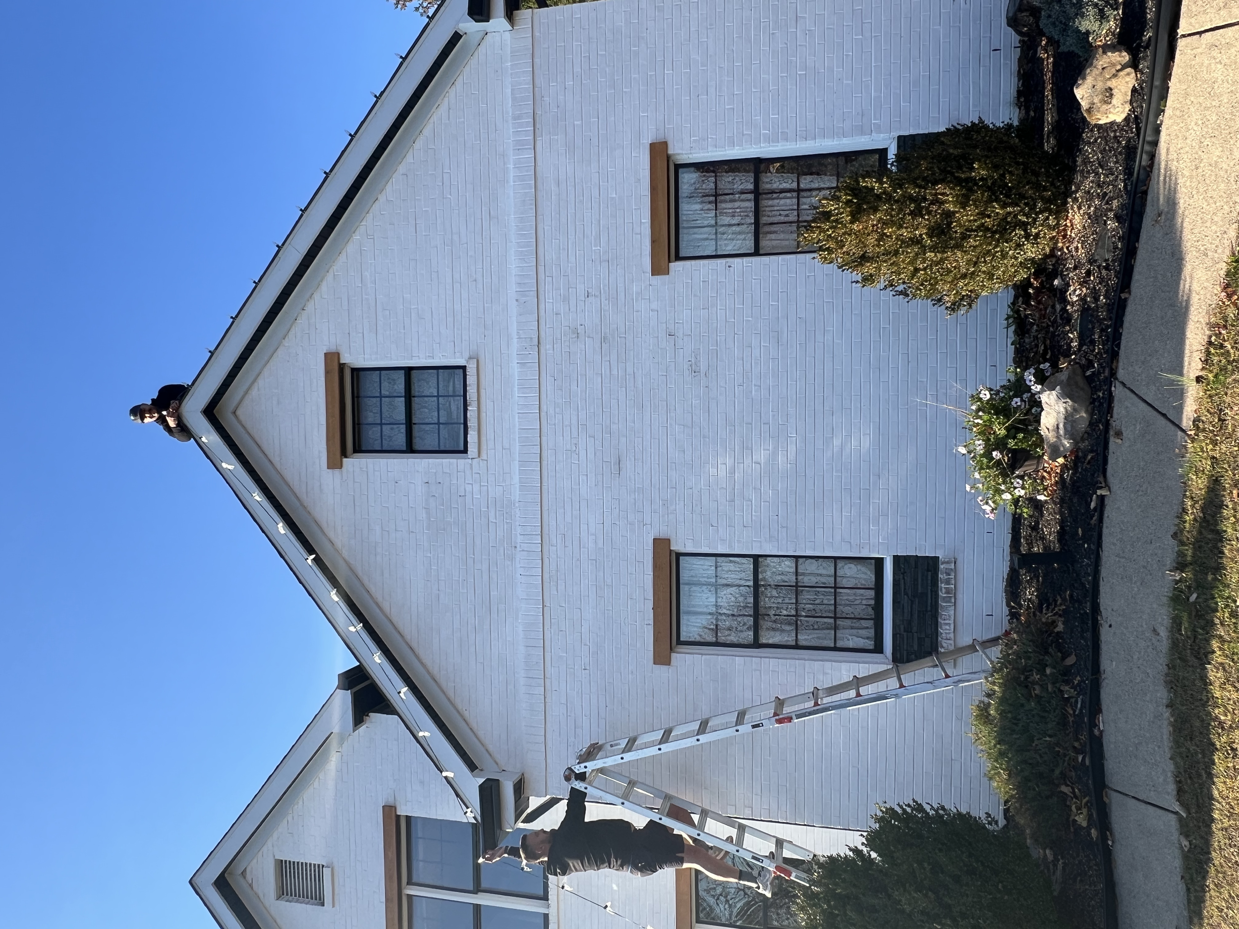 A white house with black accents house decorated with professional commercial grade Christmas light service near me. Installing Christmas lights to commercial and residential clients. 