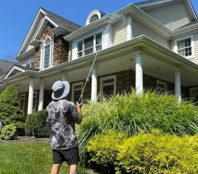 Professional pressure washing a residential house exterior