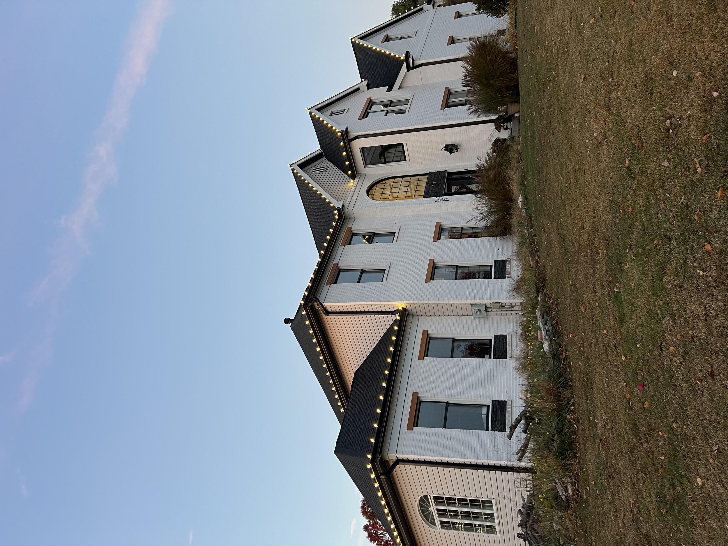 A white house with black accents house decorated with professional commercial grade Christmas light service near me. Installing Christmas lights to commercial and residential clients. 