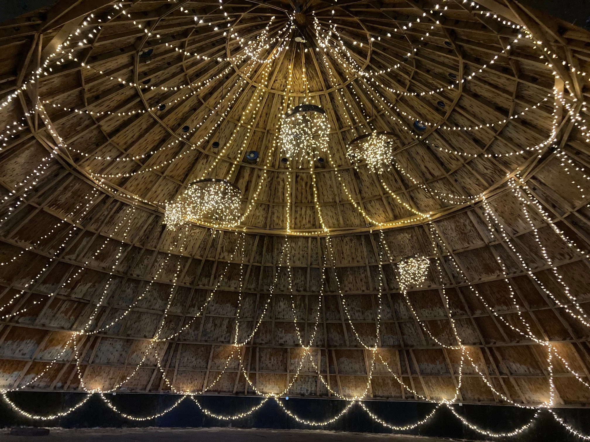 Wooden ceiling decorated with hanging and string white Christmas or holiday lights and chandeliers, creating a festive ambiance.