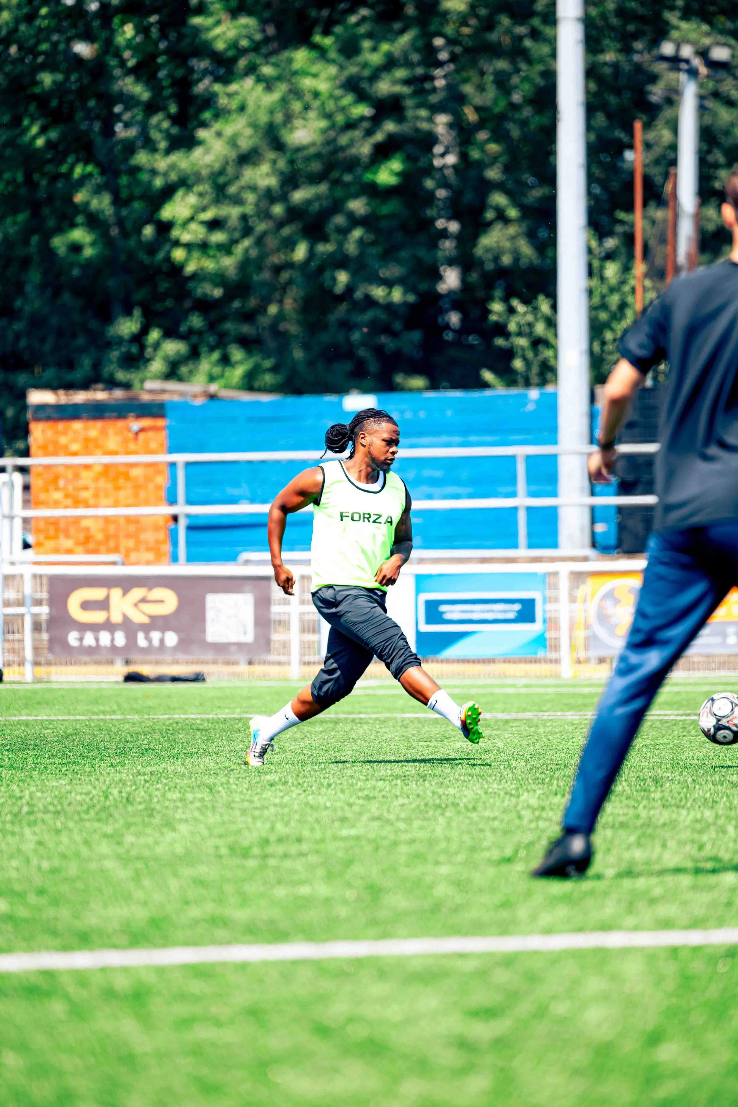 Soccer player in a neon green jersey labeled 'FORZA' running on a green field.
