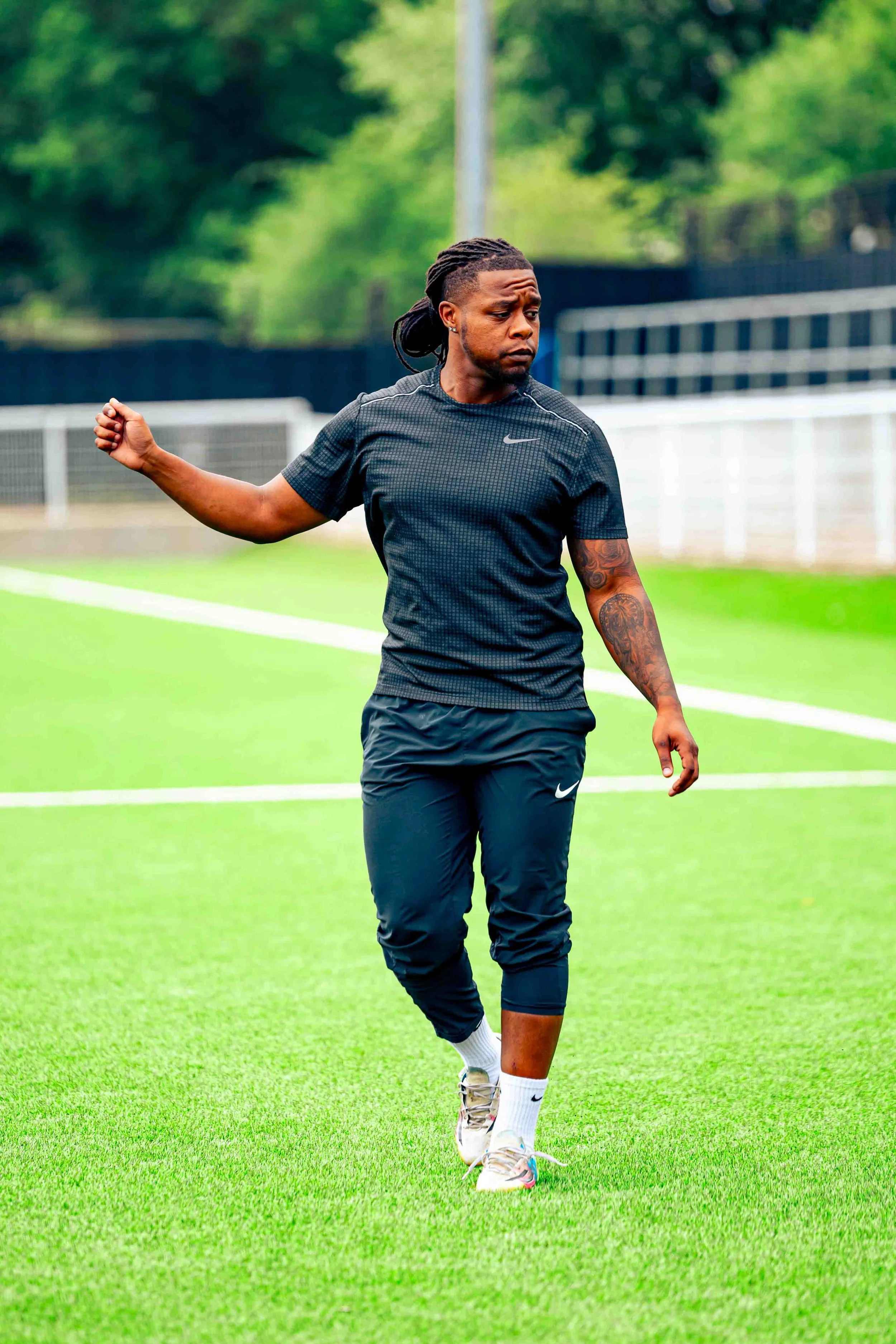 A man in athletic clothing walking on a soccer field.