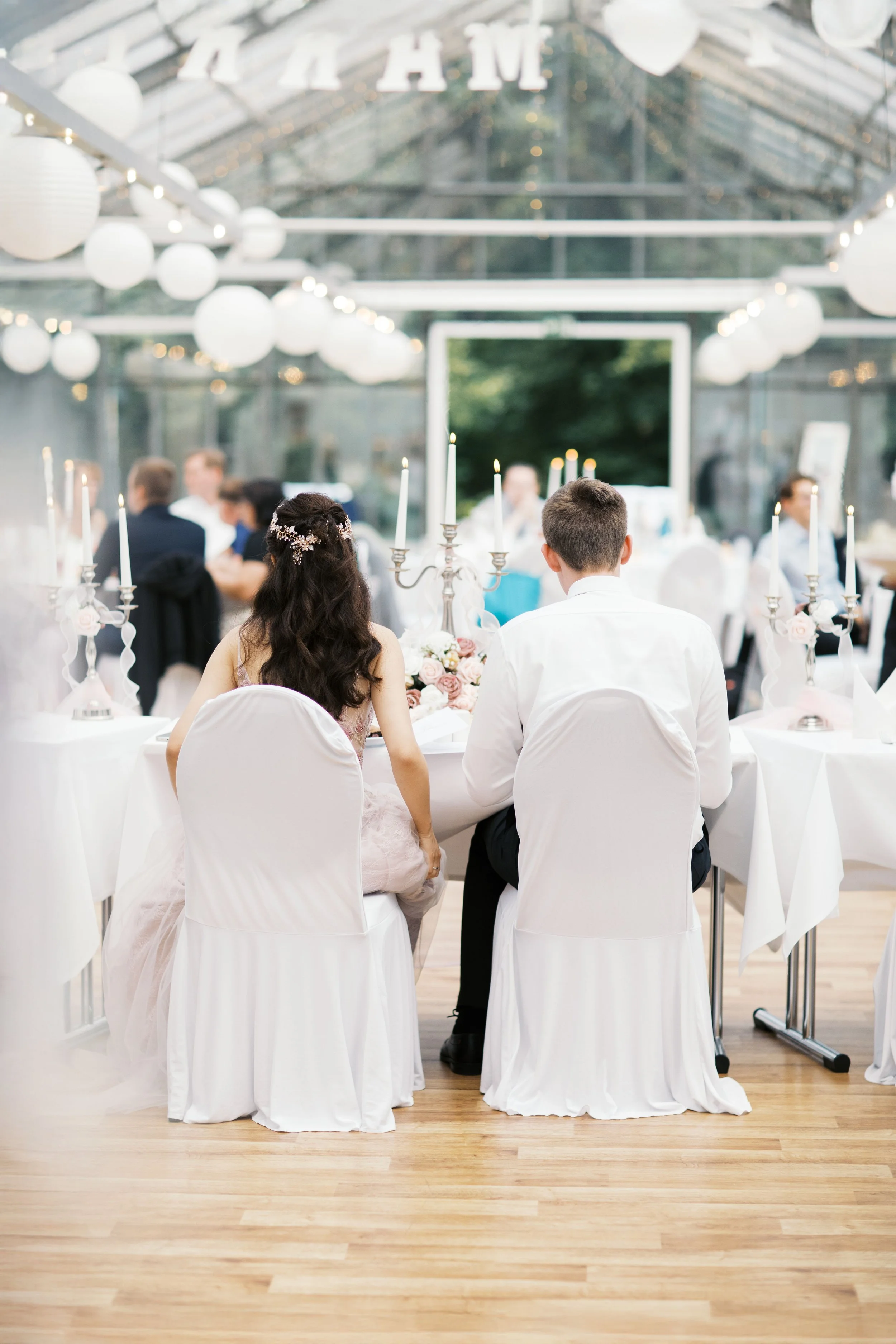 A wedding couple sitting at their reception dinner in Berlin.