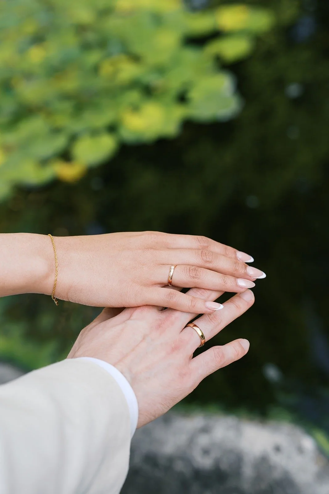 Couple with wedding rings on their hand over a pond at Gut Schloss Golm