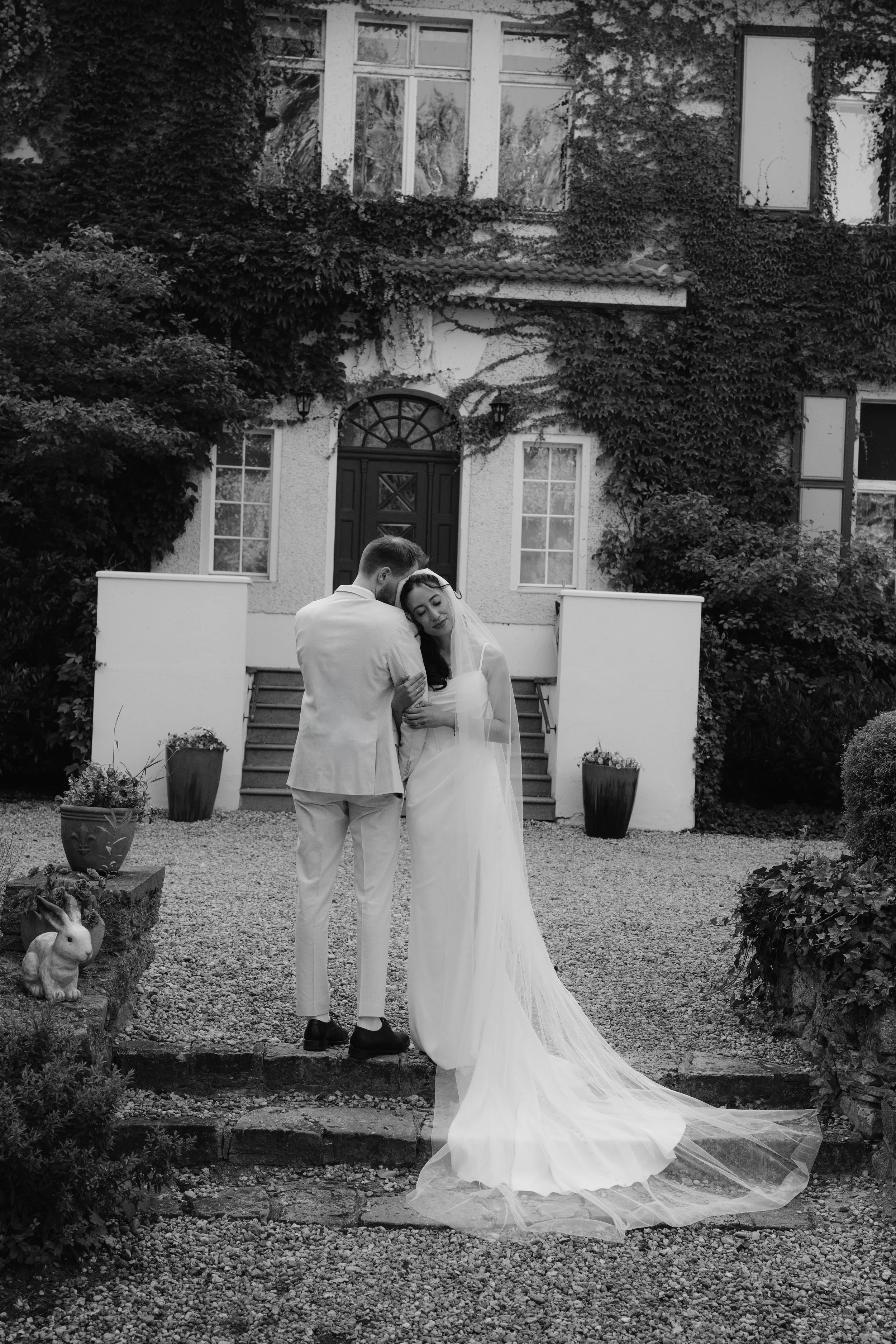 Bride leaning her head on the groom's shoulder in front of Gut Schloss Golm's estate