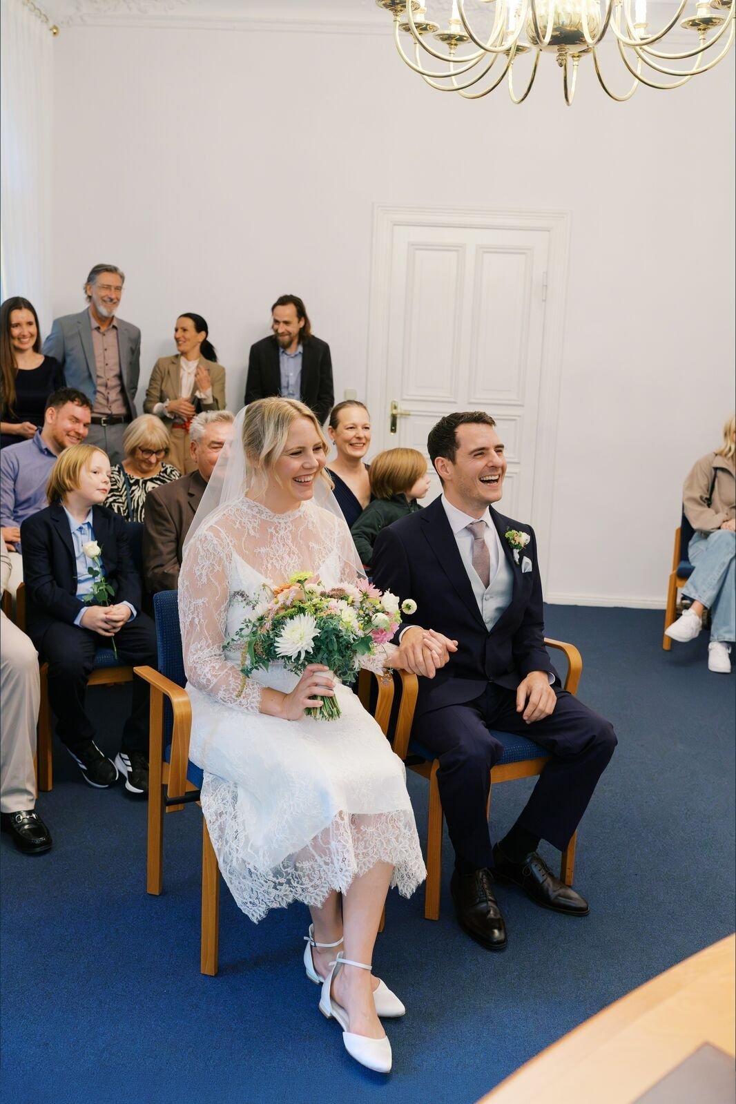 Couple sitting listening to officiant during their ceremony inside Hochzeitsvilla in Berlin