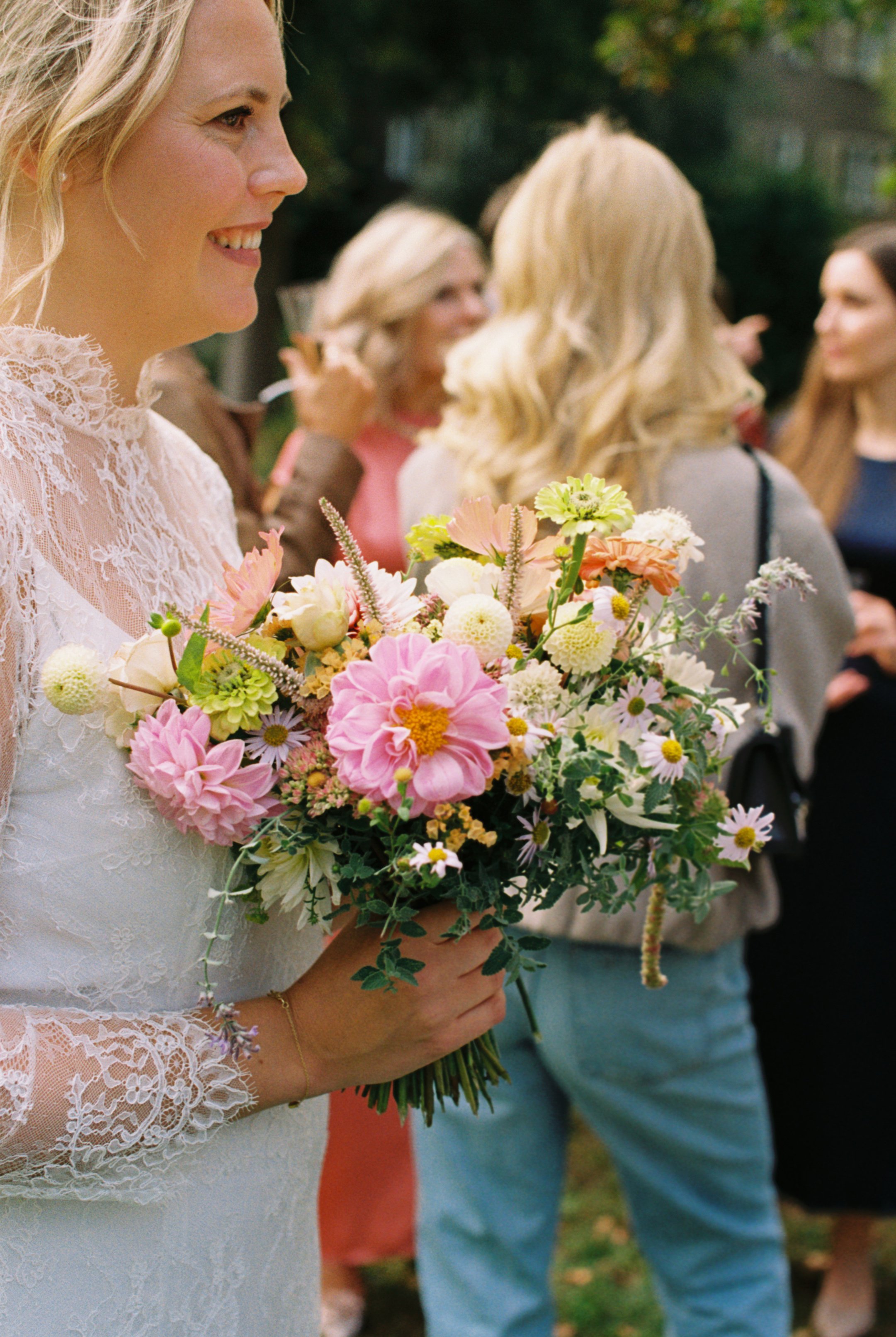 Bride holding her bouquet and talking to guests outside of Hochzeitsvilla