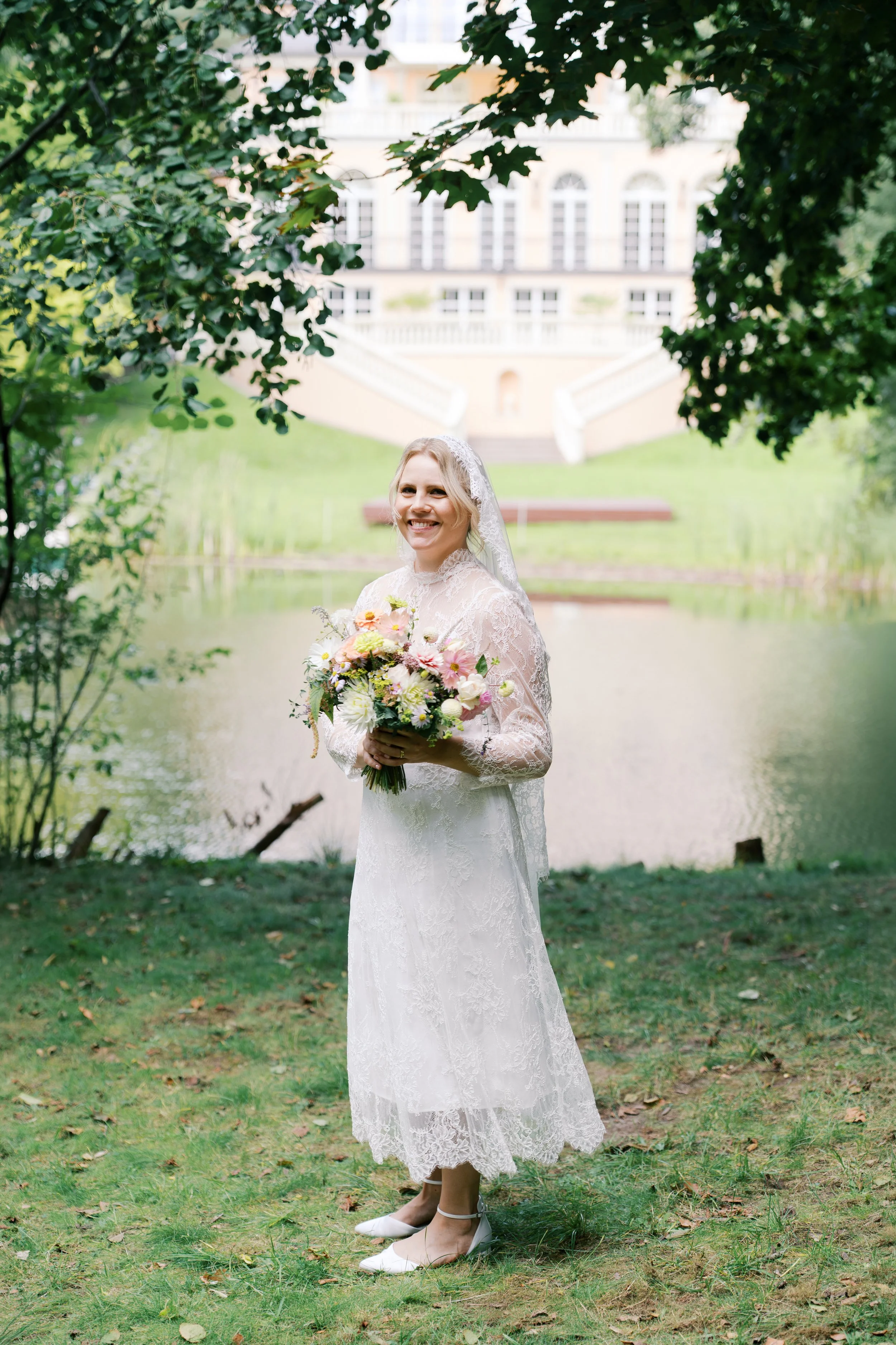 Bride standing in front of a lake and smiling