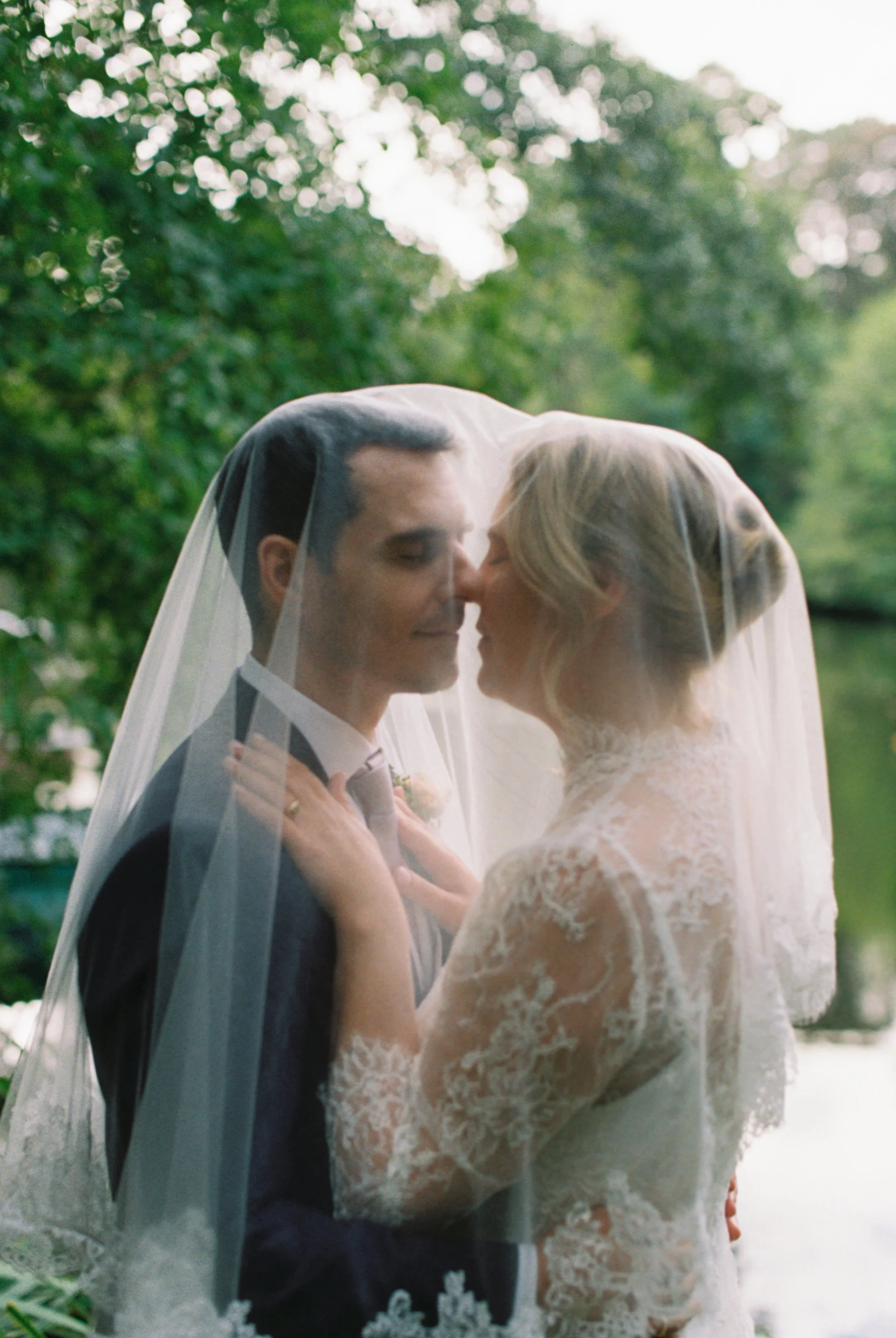 Bride and groom standing under her veil for a romantic shot