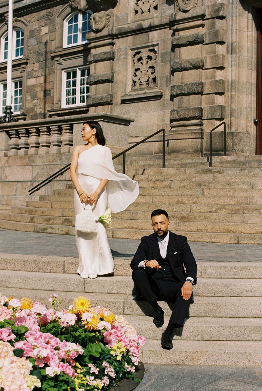 Film wedding photograph of a couple posing in front of a historic building in Copenhagen.