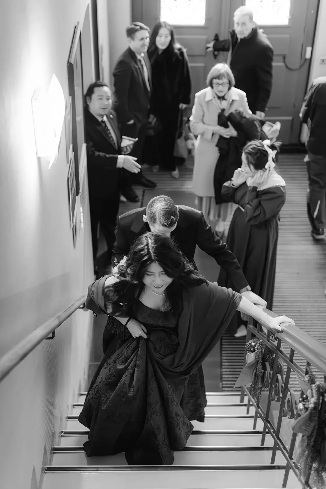a bride and groom in wedding attire walking upstairs while guests gather at Standesamt in Berlin, Germany