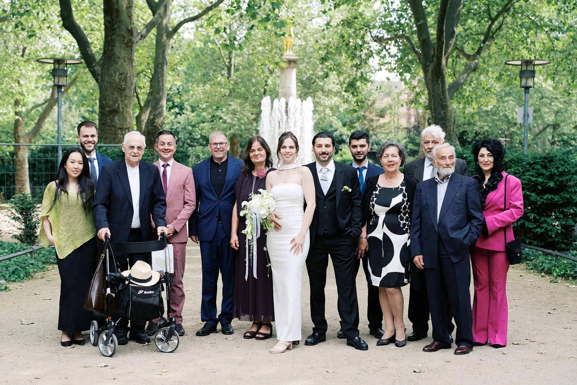 A family group photo of a wedding in front of the golden deer fountain in Schöneberg, Berlin.