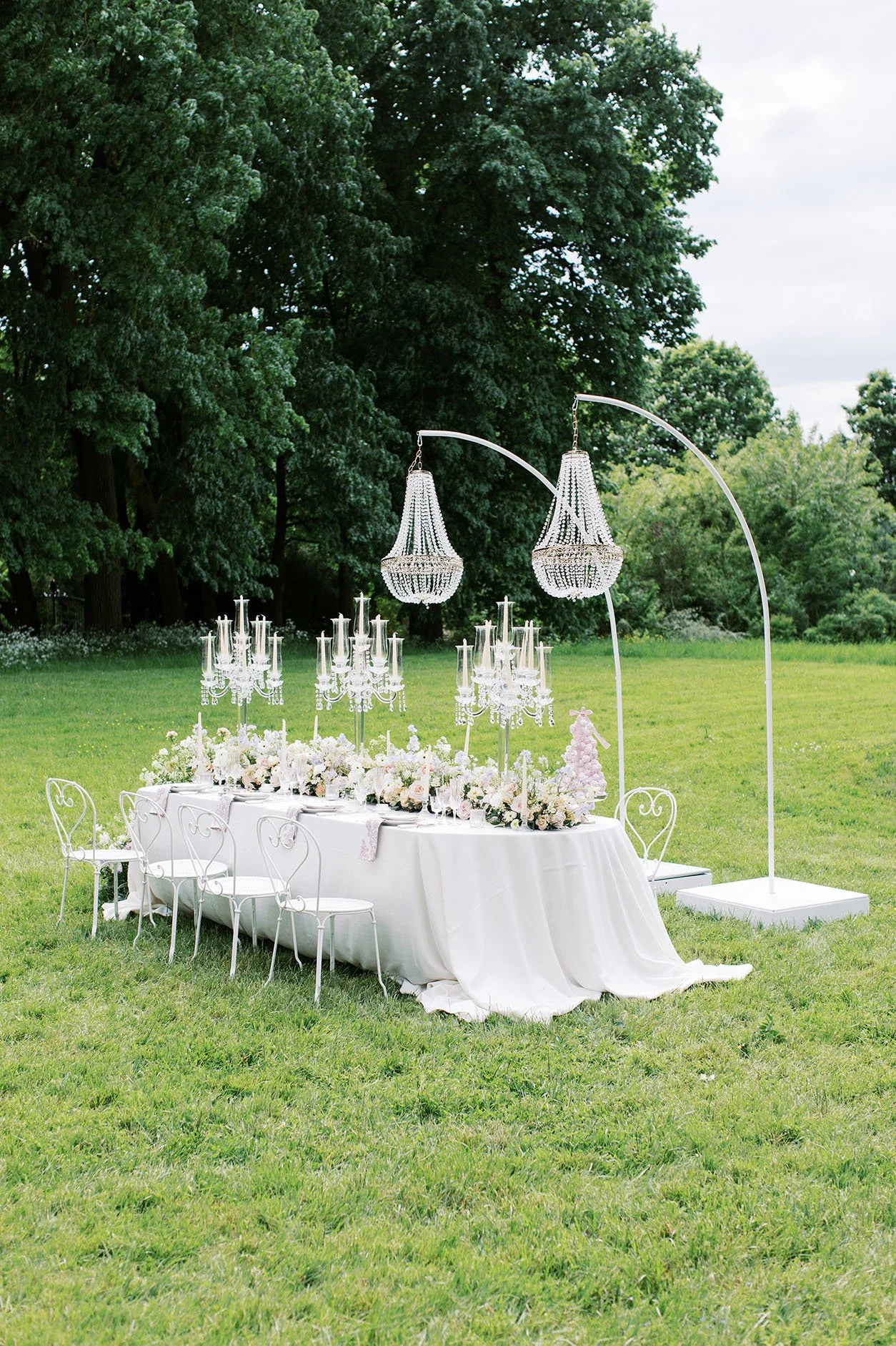 Wedding dinner table setup for an intimate Berlin wedding in a garden with whimsical florals, crystal candles and crystal chandeliers.