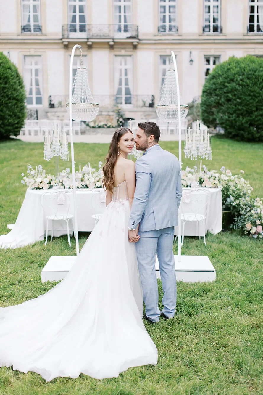 A couple in wedding attire standing close to each other, in front of a beautiful table wedding setup