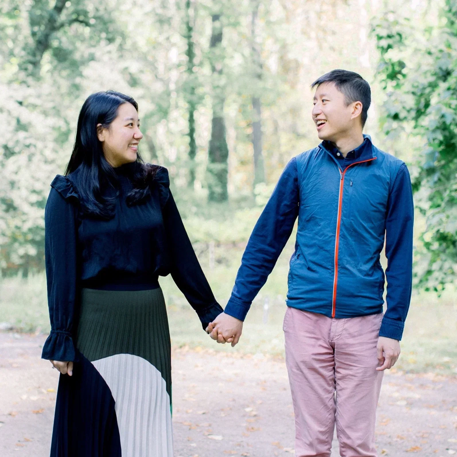A smiling couple peeking from behind a column.