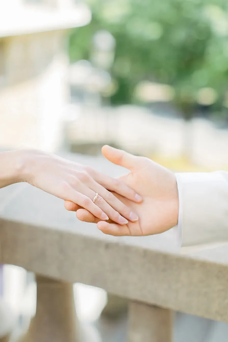 Two hands holding together with a focused feature on the wedding ring, photo captured in Berlin