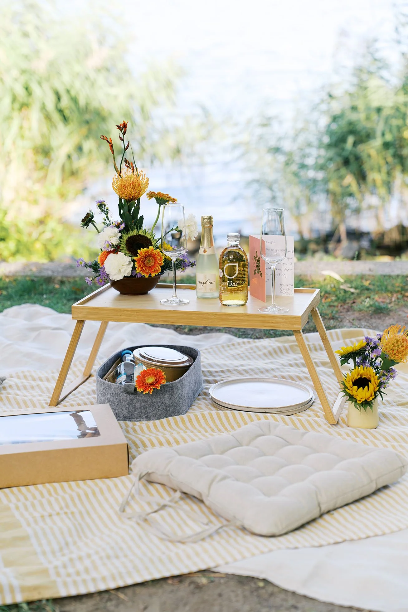 Picnic setup in a beautiful park with flowers, champagne and drinks.