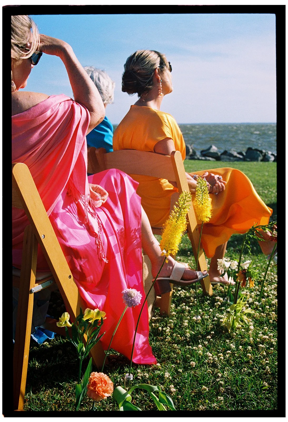 wedding guests in bright dresses with floral aisle