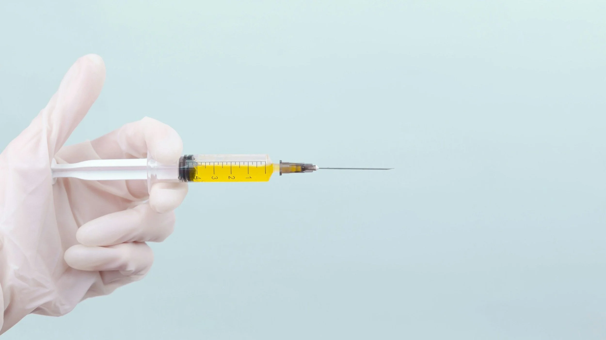 Syringe held in a gloved hand.