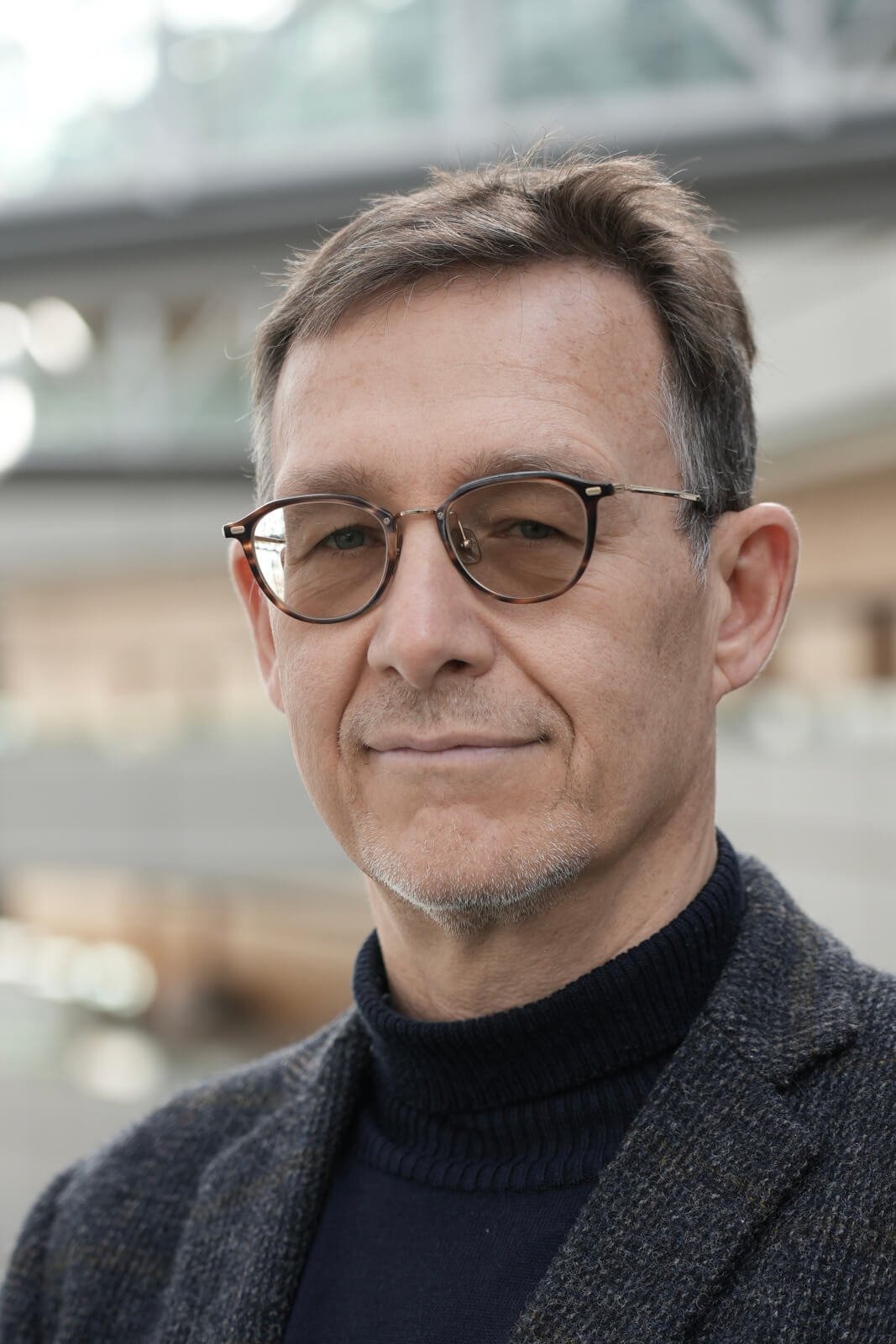 Portrait of Dan Slater, Co-Founder and Managing Director of The Delphi Network, wearing glasses and a dark turtleneck with a blazer, symbolizing trusted business intelligence in Tokyo.