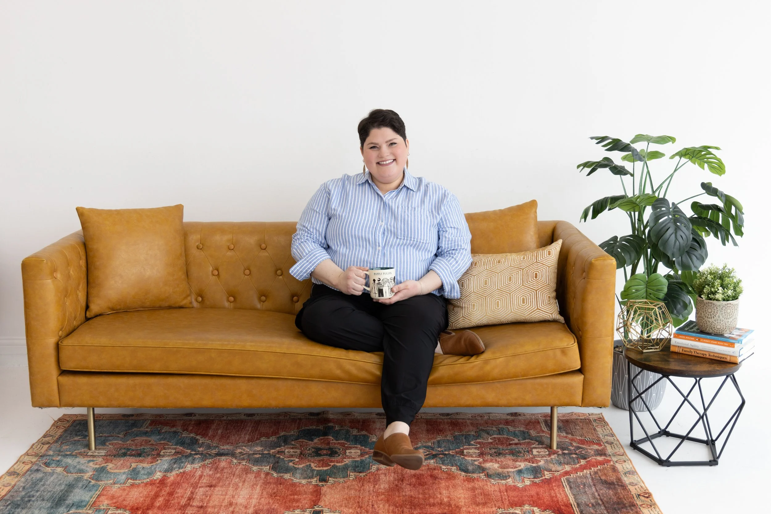 An affirming therapist in Plano provides lgbtqia therapy while sitting on a couch holding a cup of tea.