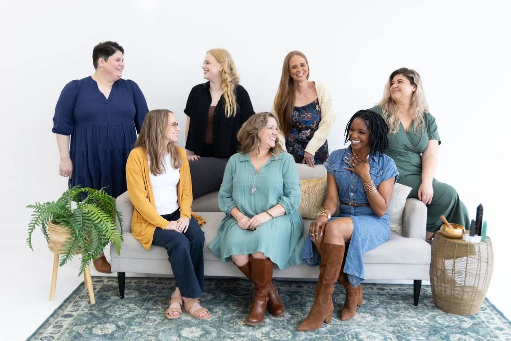 Counselors who provide relationship trauma therapy sit around a couch and talk with each other.