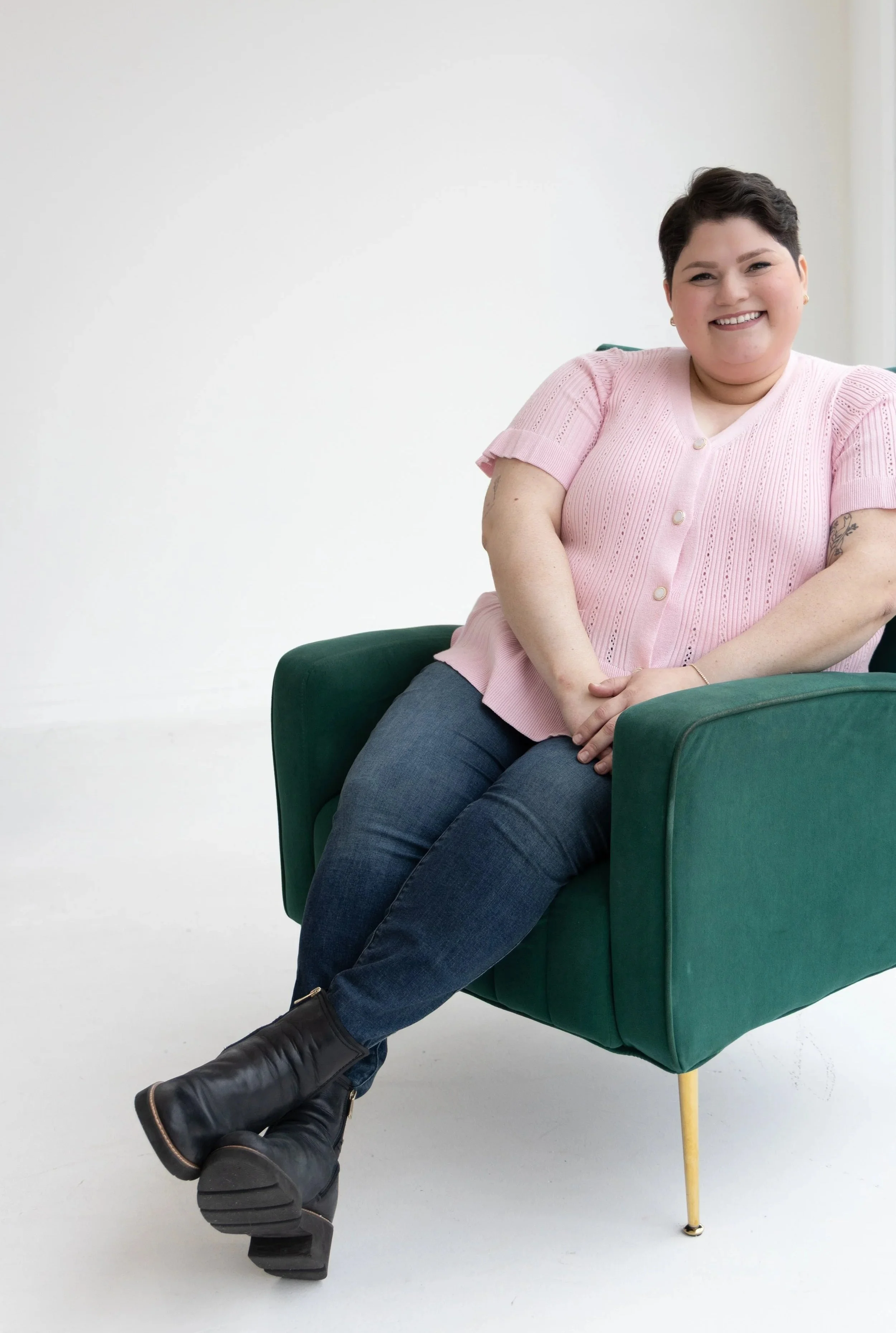 A therapist in Plano who provides eating disorder help sitting in a green chair looks ahead while smiling.