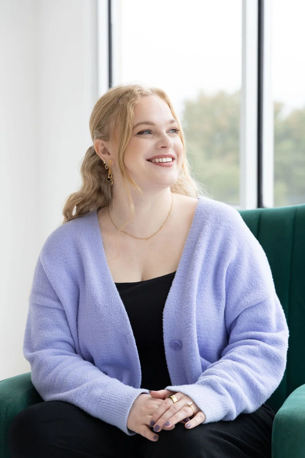 A therapist who provides couples therapy in Dallas looks out a window smiling.